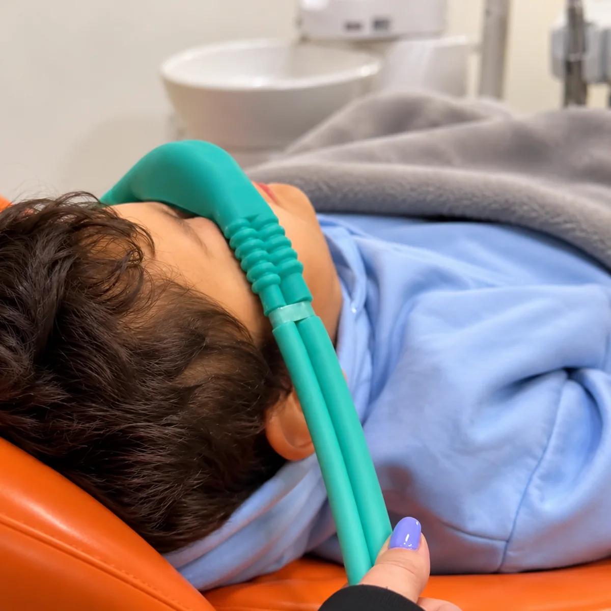 Imagem digital de paciente usando máscara nasal para sedação com óxido nitroso em cadeira odontológica laranja